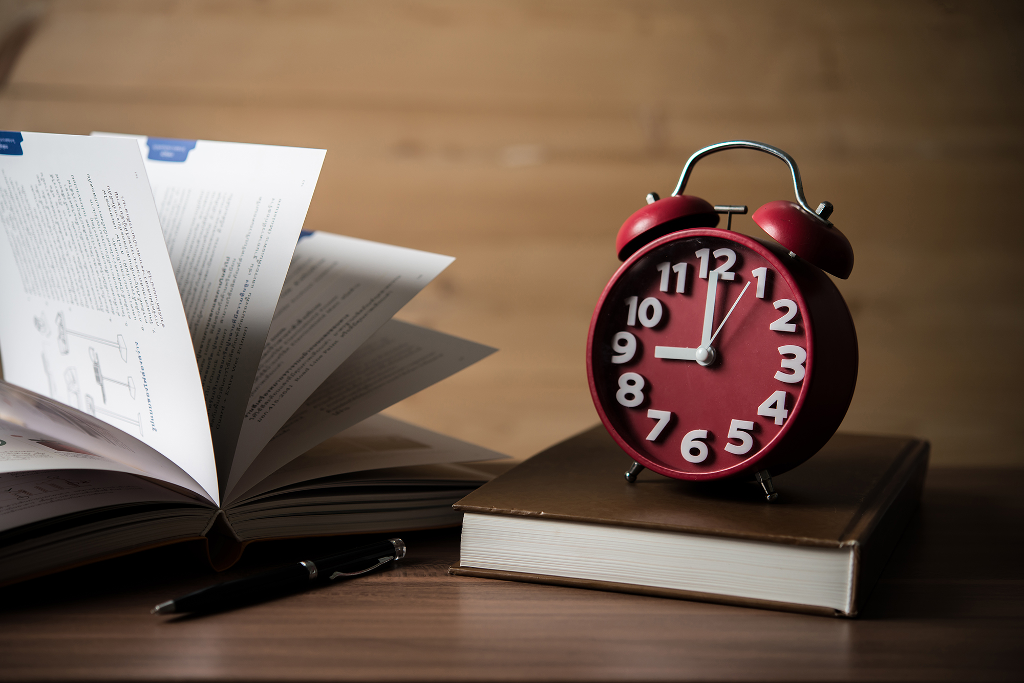 Books and alarm clock on wooden table. Education concept.
